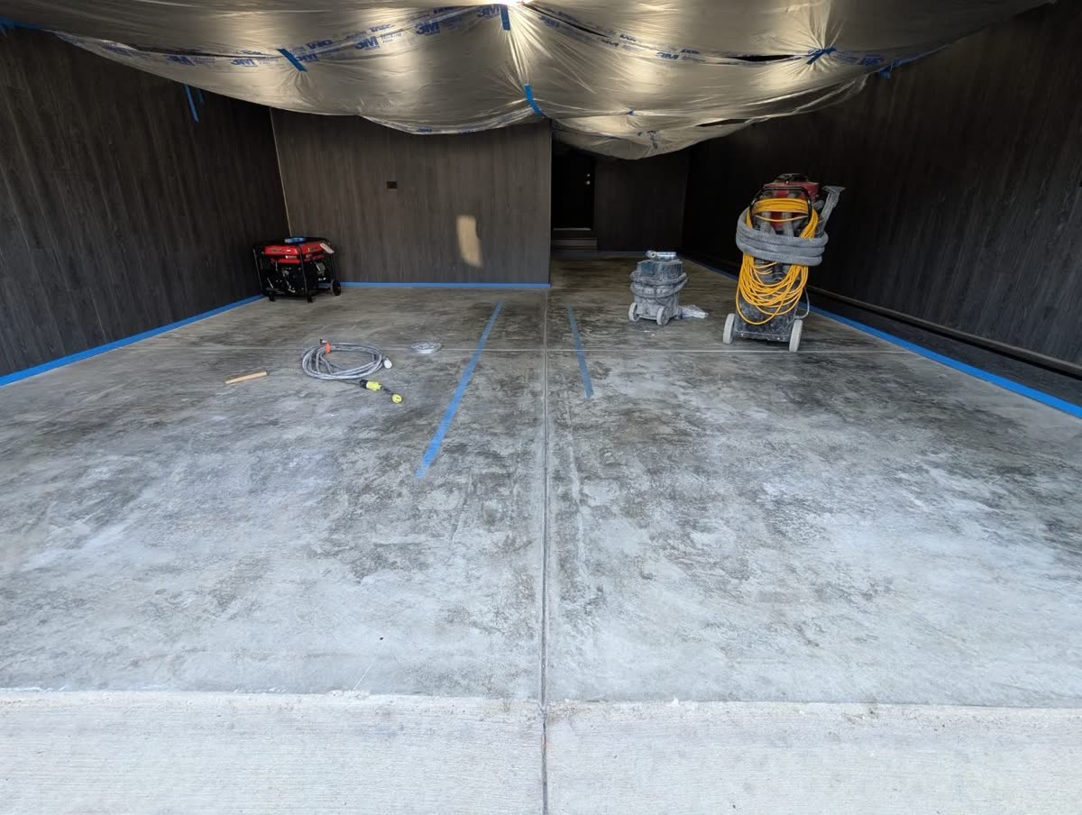 Before: bare concrete garage floor taped off for prep